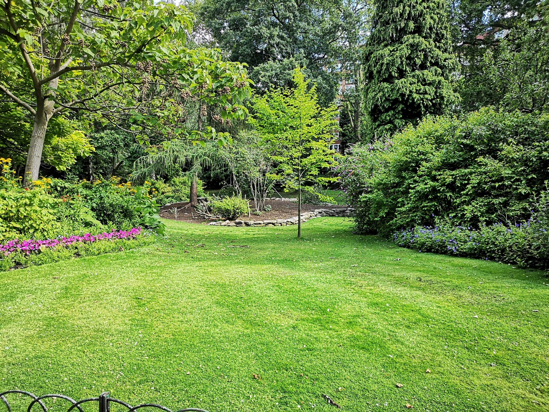 Großzügige grüne Gartenanlage mit Rasen und vielfältiger Bepflanzung