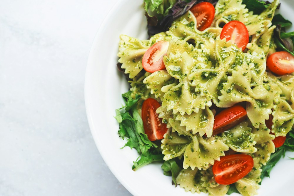 Pasta mit grünem Pesto, Tomaten und frisch geriebenem Käse